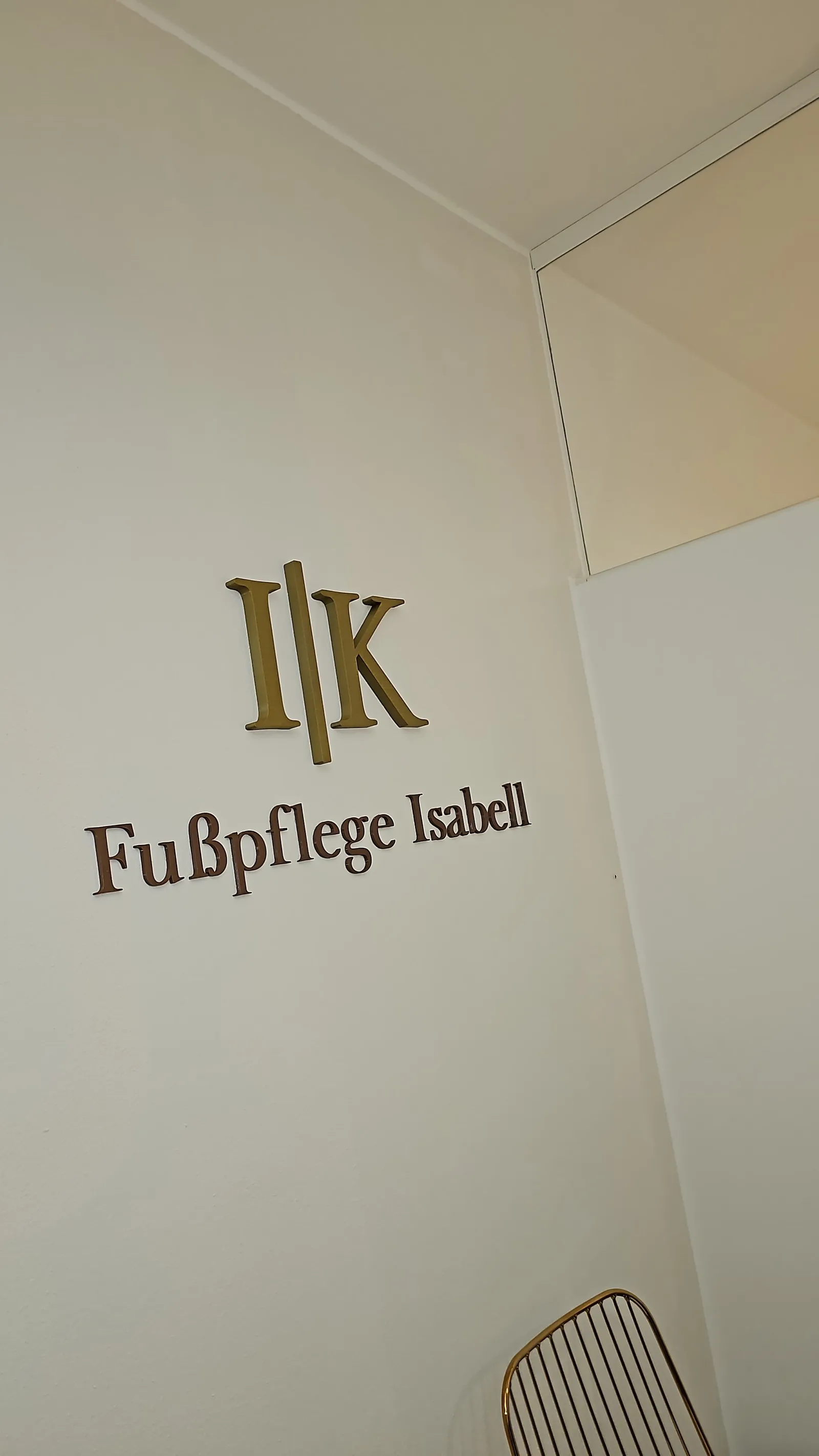 Goldene Wortmarke und Behandlungsstuhl im Studio von I|K Fußpflege Isabell